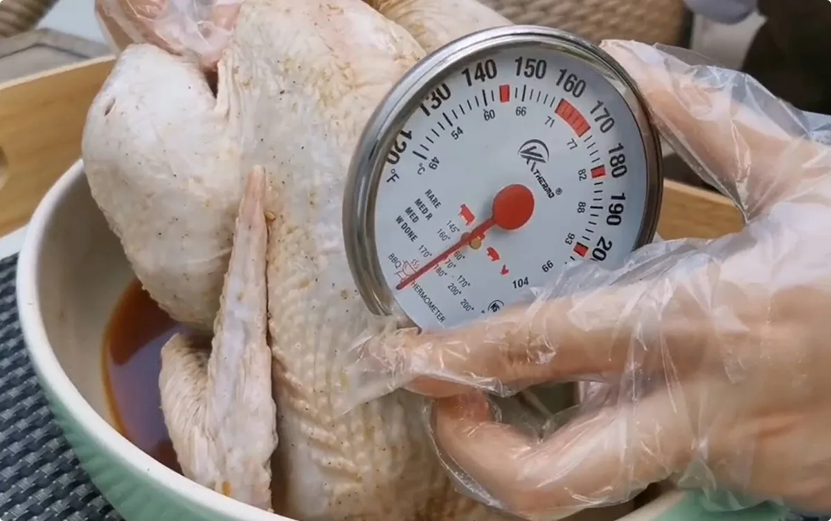 inserting meat thermometer into turkey breast